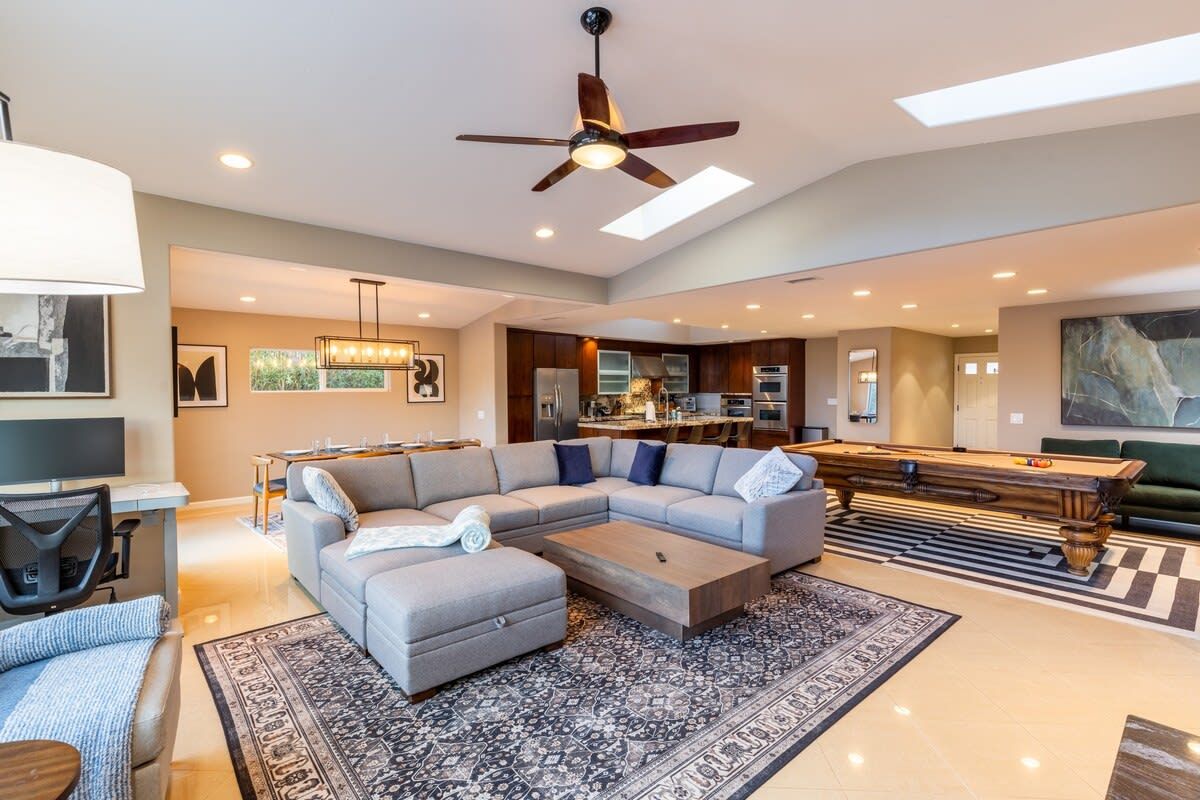 A modern living room with a sectional sofa, a coffee table, and a pool table.