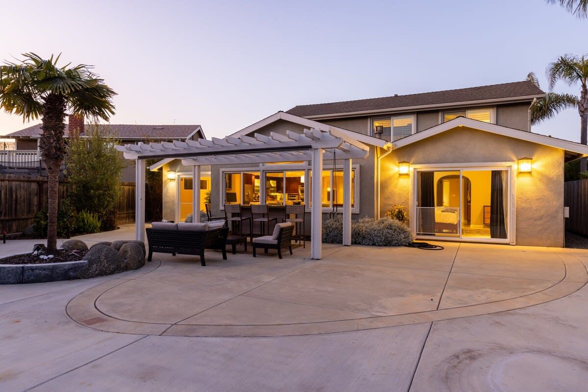 A residential property with a covered patio area, a dining setup, and a house entrance.