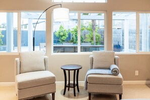 Una habitación con dos sillones, una mesita redonda y una lámpara de pie.