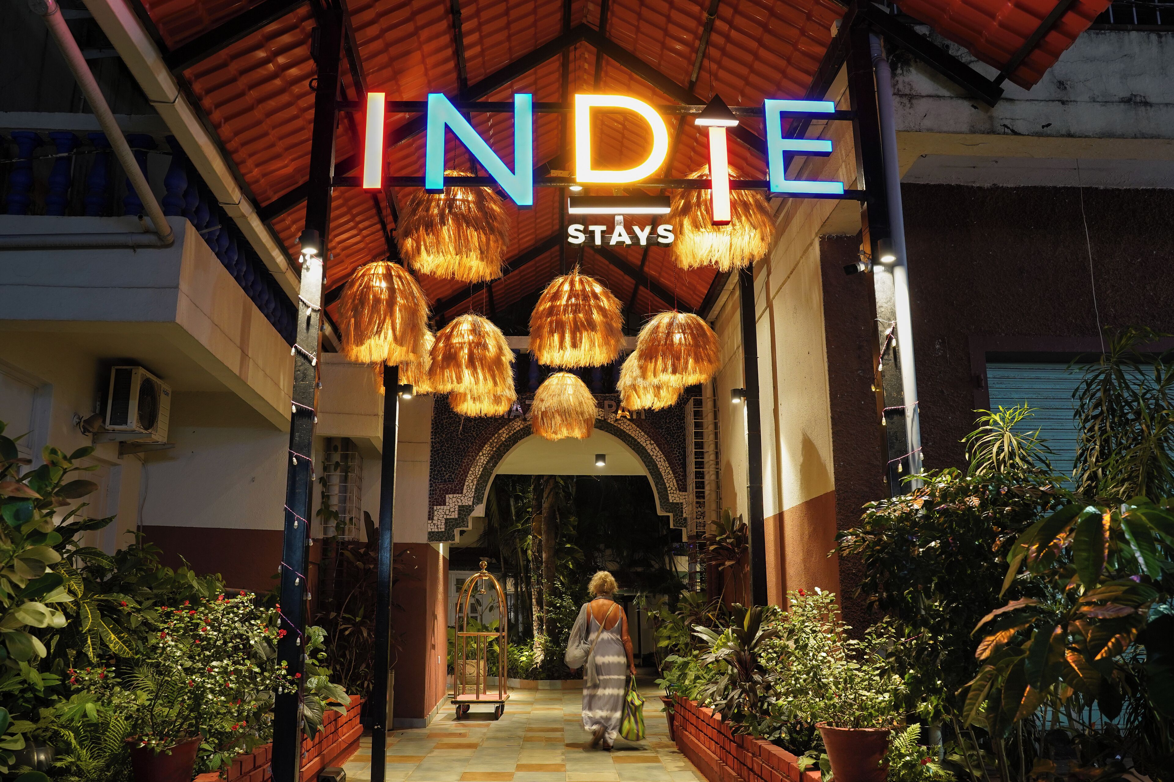 A hotel entrance with a sign reading "INDIE STAYS" and a person walking inside.