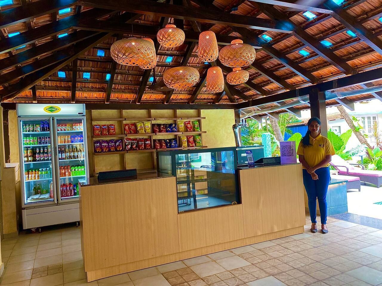 A food kiosk with a wooden counter, a refrigerated beverage display, and a variety of snacks.