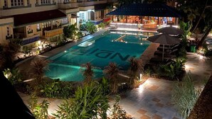A hotel with a swimming pool, outdoor seating, and a well-lit patio area. - Indie Stays Goa (Candolim)