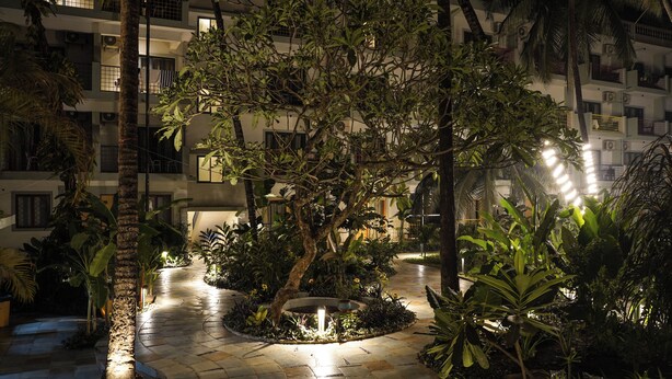 A courtyard with a central fountain, surrounded by lush greenery and palm trees. - Indie Stays Goa (Candolim)