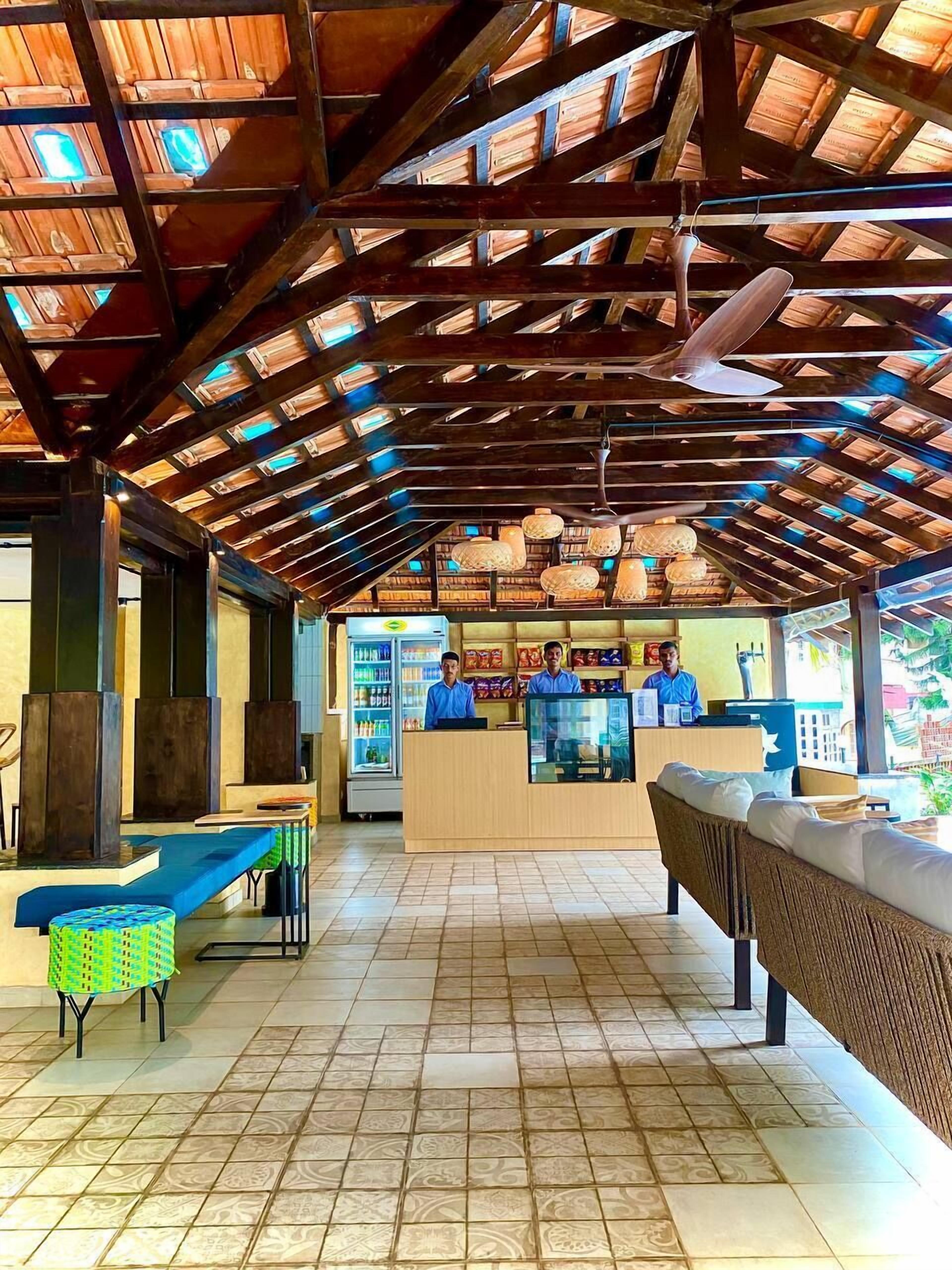 Un ristorante con soffitto in legno a volta, pavimento in piastrelle e un bancone con personale al servizio.