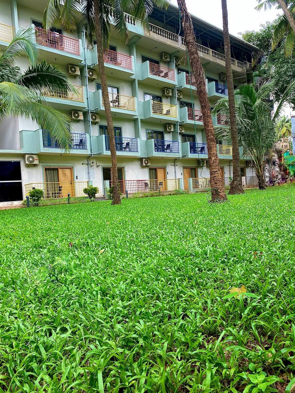 A multi-story building with balconies, air conditioning units, and a well-maintained lawn.