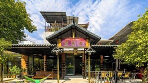 A traditional-style building with a covered entrance, outdoor seating area, and potted plants. - Yangshuo Xingping Our Inn-Near 20 Yuan Background (Yangshuo)
