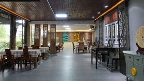 A spacious restaurant with wooden ceiling and walls, featuring traditional decor and multiple dining tables. - Yangshuo Xingping Our Inn-Near 20 Yuan Background (Yangshuo)