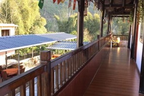 A wooden balcony with a view of a traditional house and trees. - Yangshuo Xingping Our Inn-Near 20 Yuan Background (Yangshuo)