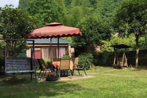 A covered outdoor seating area with a table and chairs, a swing set, and a fenced play area. - Yangshuo Xingping Our Inn-Near 20 Yuan Background (Yangshuo)