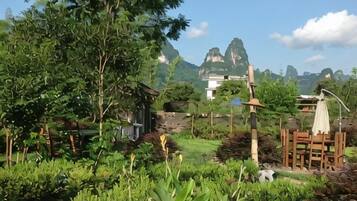 A garden with a wooden deck, a gazebo, and a mountain view.