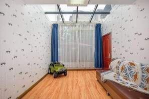 A room with a skylight, a toy car, a sofa, and patterned wallpaper.
