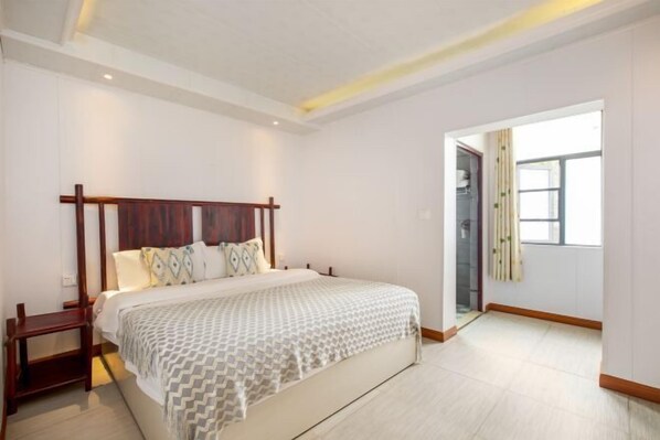 A bedroom with a large bed, wooden headboard, and a bedside table.