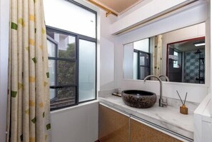 A modern bathroom with a large window, a round sink, and a mirror.