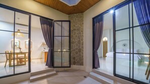 Amplia sala de estar con un muro de acento de piedra, puertas correderas de vidrio y un comedor con mesa y sillas.