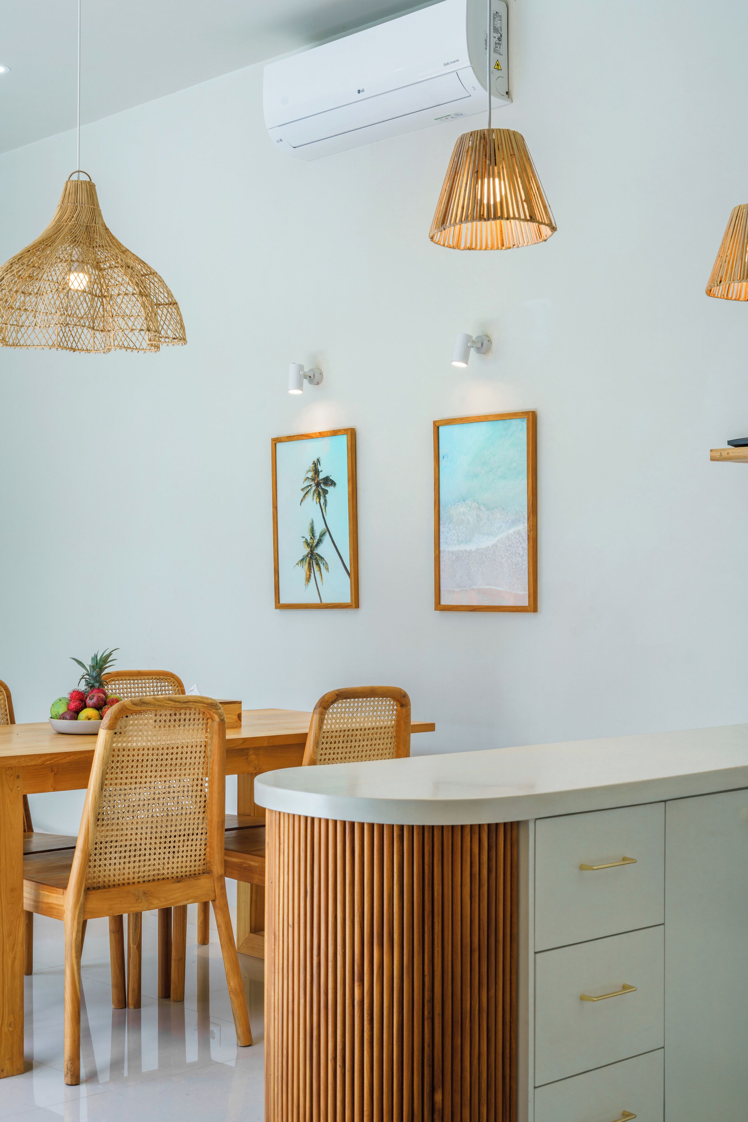 Et moderne spiseområde med et rundt bord, fletstole og et indbygget skab med skuffer.