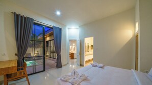 Habitación de hotel con cama, escritorio y puerta corrediza de vidrio que da a un balcón.