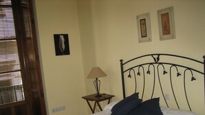 Un dormitorio con cama, mesita de noche, lámpara y dos cuadros en la pared.