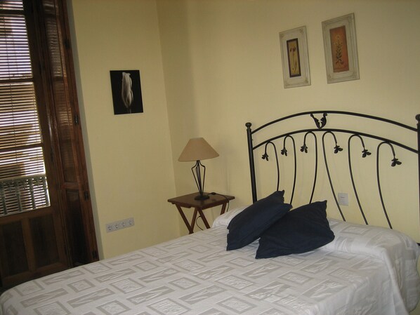 Une chambre à coucher avec un lit, une table de chevet, une lampe et deux tableaux encadrés accrochés au mur.