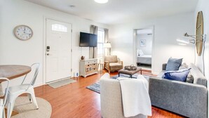 A living room with a sofa, armchair, TV, and a dining area with a table and chairs.