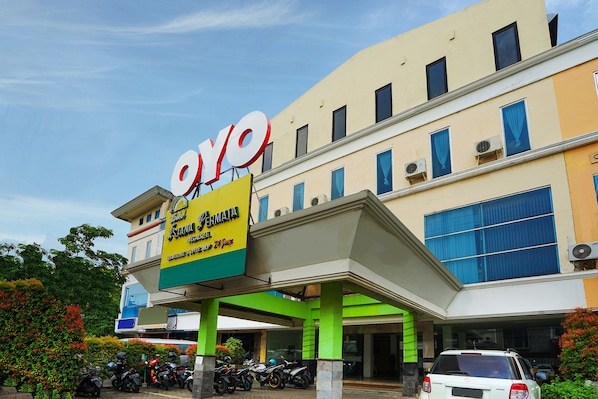 A building with a large sign reading "OYO" and "Fermina Hotel." There are several motorcycles parked in front, and the building has multiple windows and balconies.
