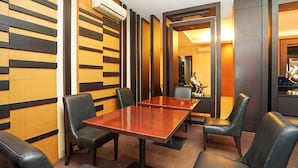 A restaurant with wooden panel walls, black leather chairs, and a central table. - Istana Permata Ngagel (Surabaya)