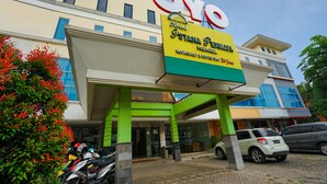 A hotel with a prominent sign, a covered entrance, and parked vehicles. - Istana Permata Ngagel (Surabaya)