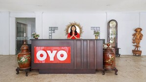 A reception desk with a 'OYO' sign, two decorative vases, a mirror, and a statue. - Istana Permata Ngagel (Surabaya)