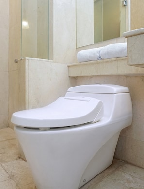 A white toilet in a bathroom with a glass shower enclosure and a towel rack above it.