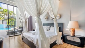A bedroom with a bed, a nightstand, a lamp, and a view of a swimming pool. - Mana Villas Nusa Dua (Nusa Dua)