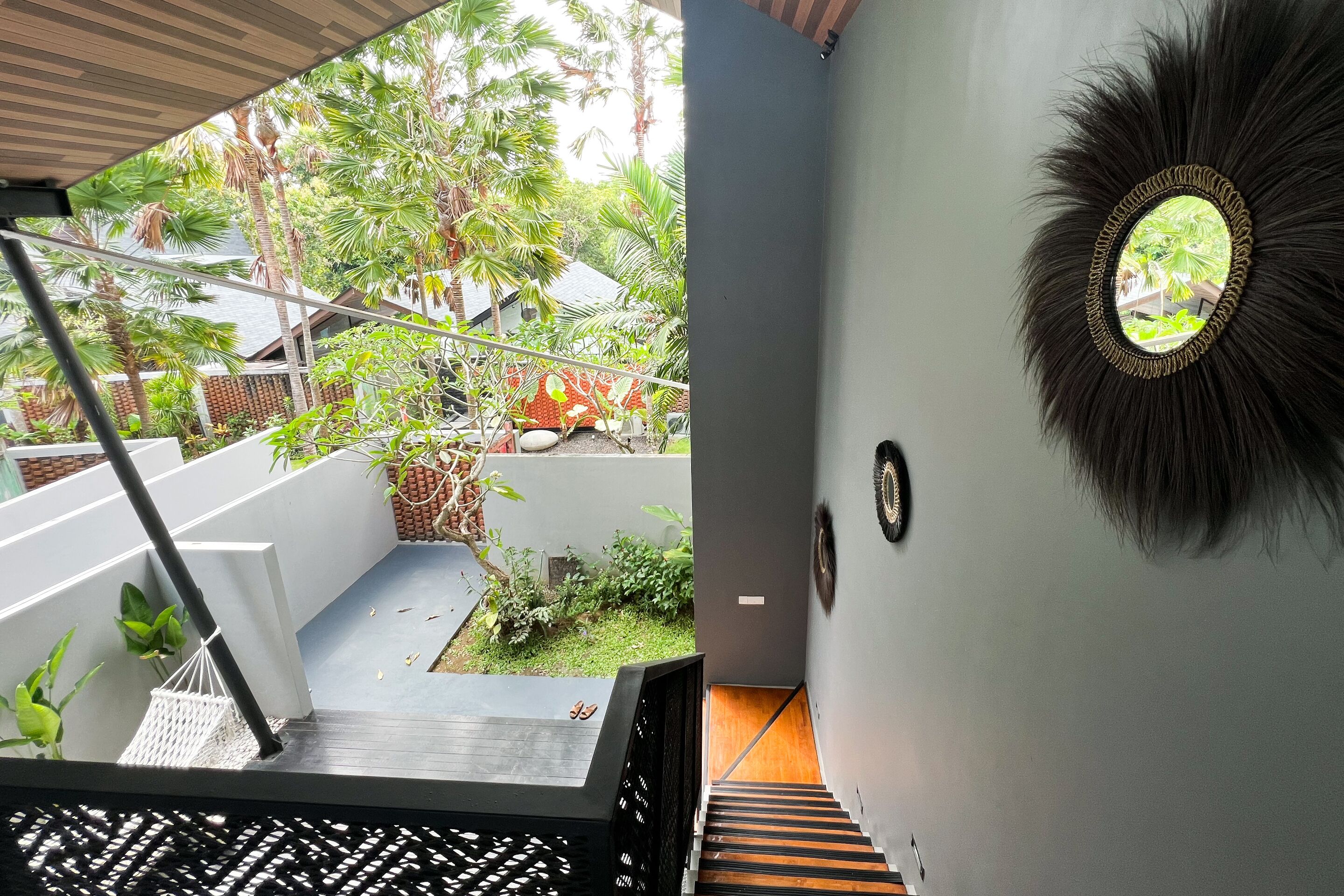 A staircase leading to a balcony with a view of a garden and a house.