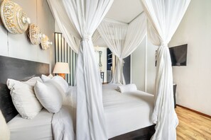 A bedroom with a four-poster bed, a bedside lamp, and a flat-screen TV on the wall. - Mana Villas Nusa Dua (Nusa Dua)