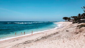 A beach with clear blue water, a sandy shore, and some trees. - Mana Villas Nusa Dua (Nusa Dua)
