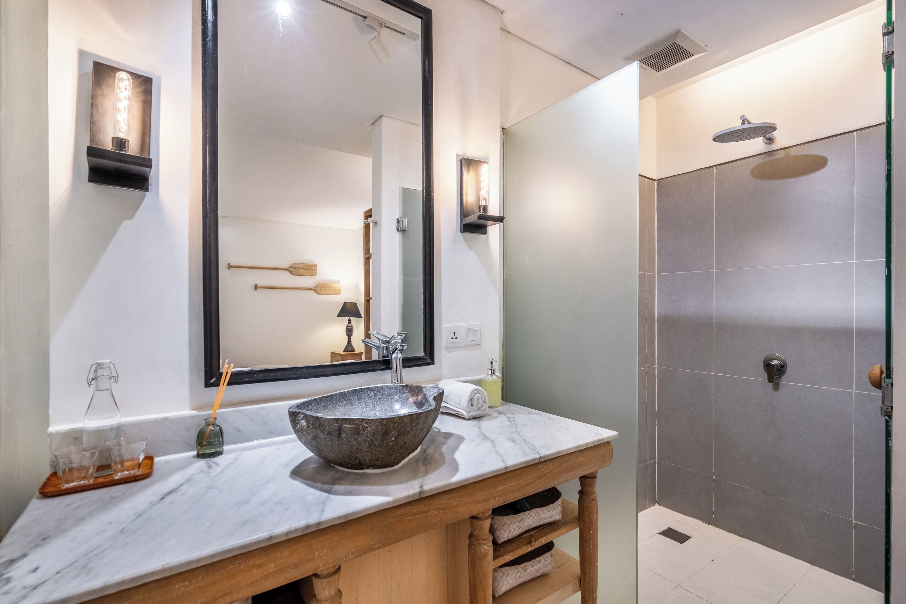 Un baño con un espejo grande, un lavabo sobre encimera, ducha y tocador de madera.