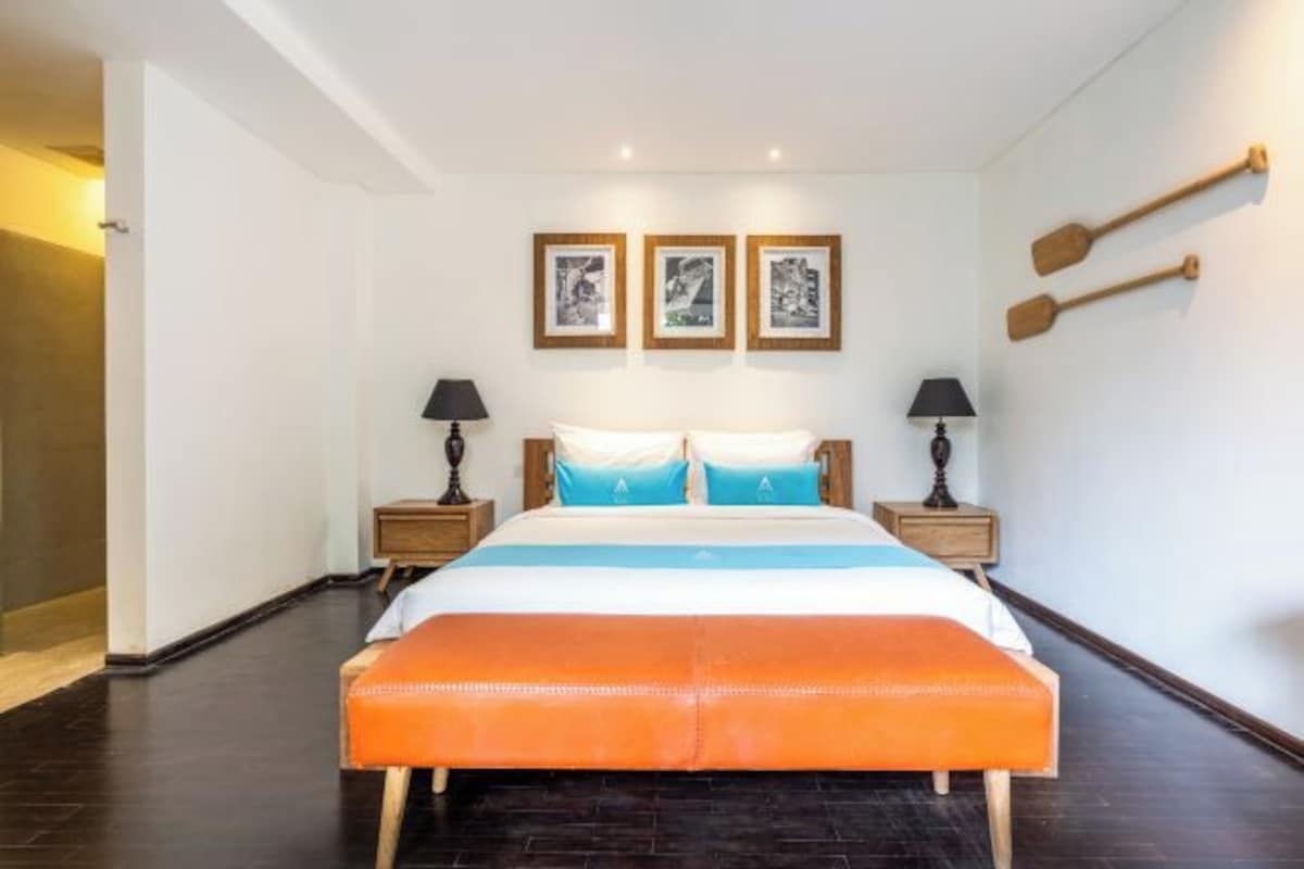 A hotel room with a large bed, two bedside tables with lamps, and three framed pictures on the wall.
