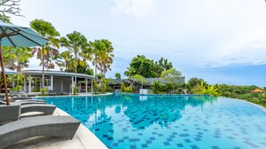 A swimming pool with tiled flooring, lounge chairs, and palm trees. - Mana Villas Nusa Dua (Nusa Dua)