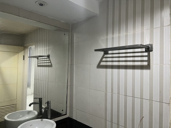 A bathroom with two sinks, a mirror, and towel racks on the wall.