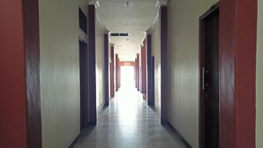 Um corredor comprido e estreito com chão de azulejos e portas em ambos os lados.