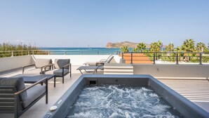 A rooftop terrace with a hot tub, lounge chairs, and a view of the sea. - Ostrakon Suites (Agia Marina)