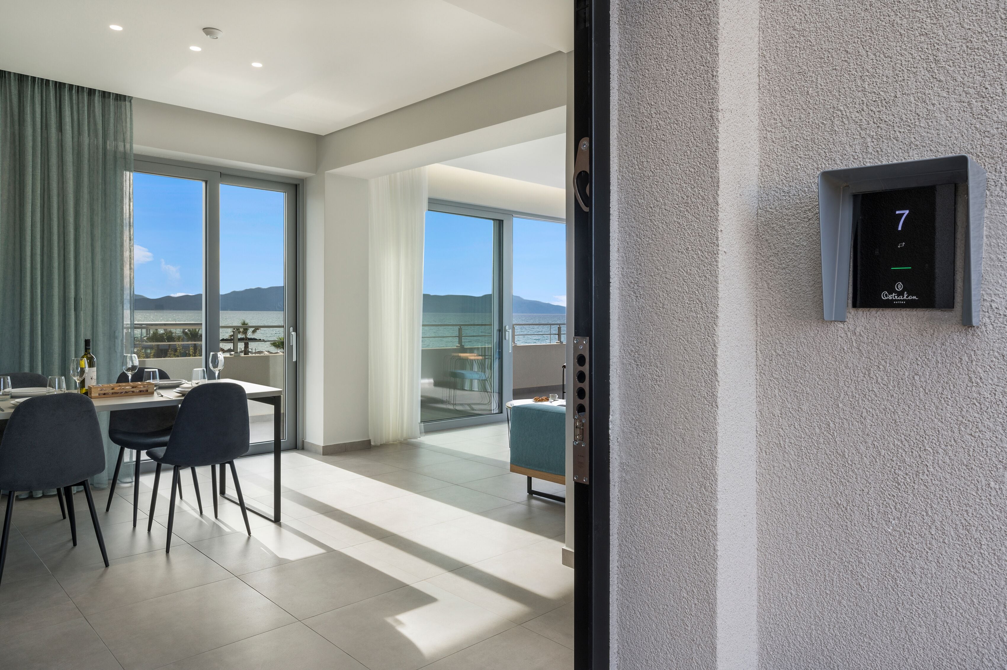 A modern hotel room with a balcony, a dining area, and a digital lock indicating room number 7.