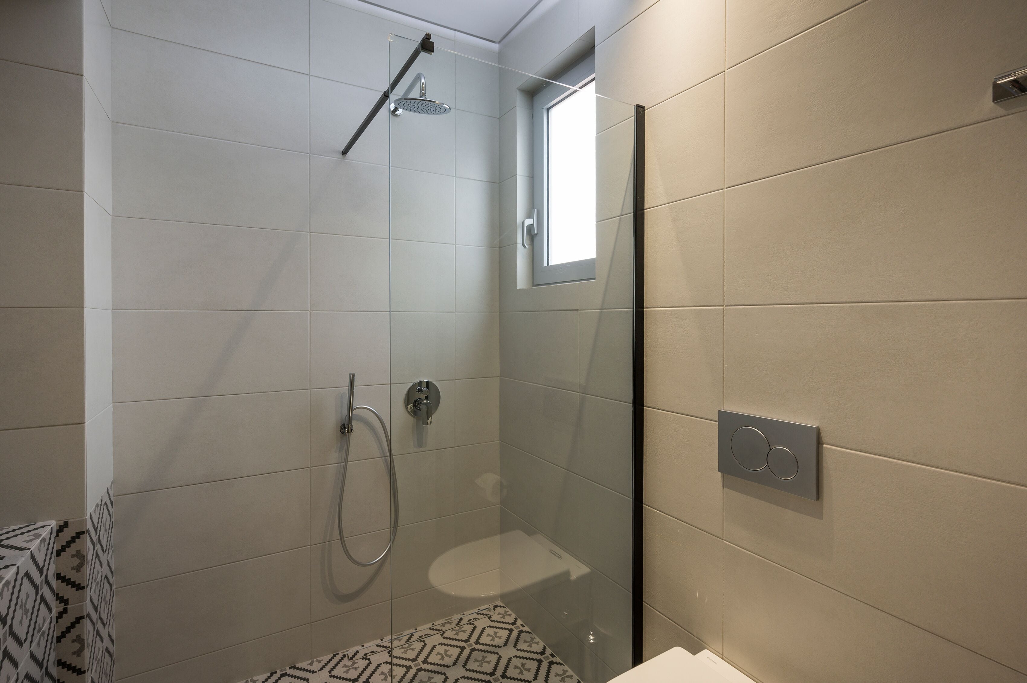 A modern bathroom with a glass-enclosed shower, a toilet, and a sink.