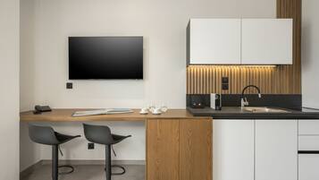 Una cocina moderna con televisor de pantalla plana, barra de madera, dos taburetes de bar y horno empotrado.