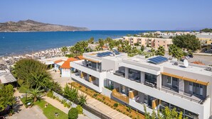 A modern hotel with multiple floors, large windows, and solar panels on the roof. - Ostrakon Suites (Agia Marina)