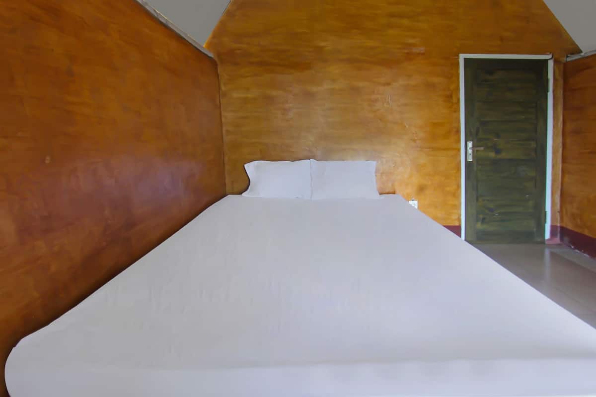 Una camera da letto con un letto grande, pareti in legno e una porta.