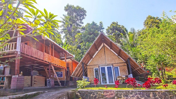 A wooden building with a sloped roof and a stone wall in front. - OYO 92419 Rejeng Homestay Near Kerta Gangga Waterfall (Gangga)