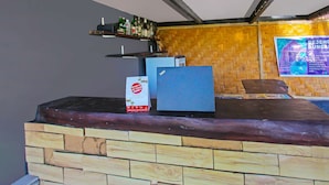 A reception area with a wooden counter, a refrigerator, and a shelf with bottles. - OYO 92419 Rejeng Homestay Near Kerta Gangga Waterfall (Gangga)