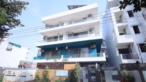 A multi-story building with a blue and white facade, multiple balconies, and a sign indicating hospitality services. - Wedlock Hotels (Gurugram)