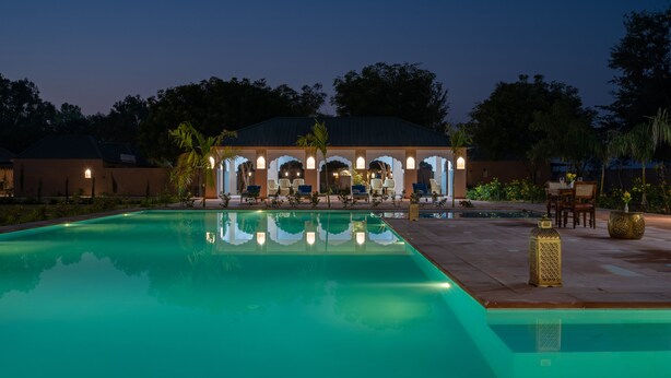Una piscina con un'area salotto coperta e lettini.