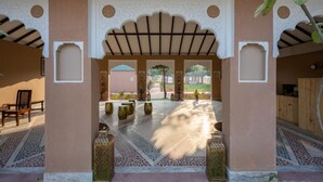 Un corridoio architettonico con archi, pavimento decorato e lanterne ornamentali.