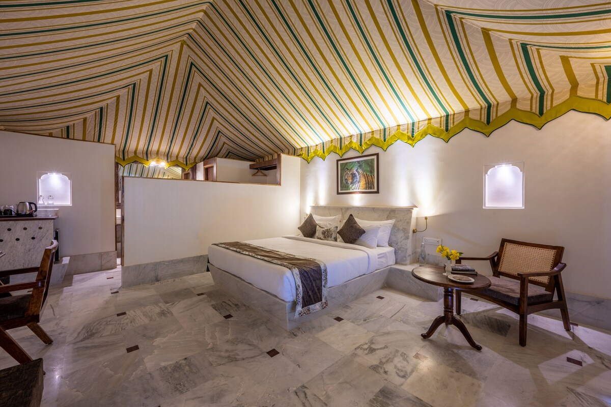A bedroom with a bed, bedside table, chair, and a painting on the wall.