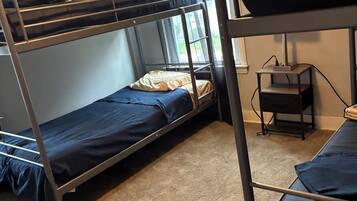 A bunk bed room with a window, a desk, and a small shelf.